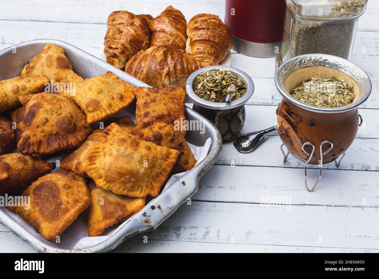 Mate, empanadas e croissant su un tavolo di legno bianco. Cena di famiglia Foto Stock