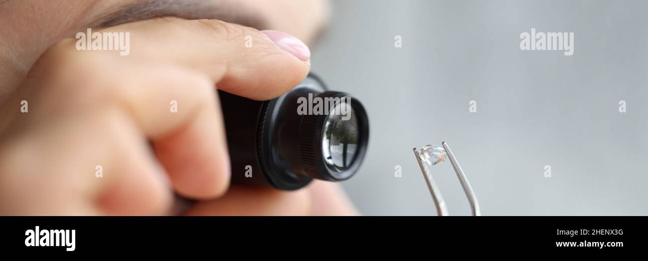 La donna guarda attraverso la lente d'ingrandimento alla pietra preziosa Foto Stock