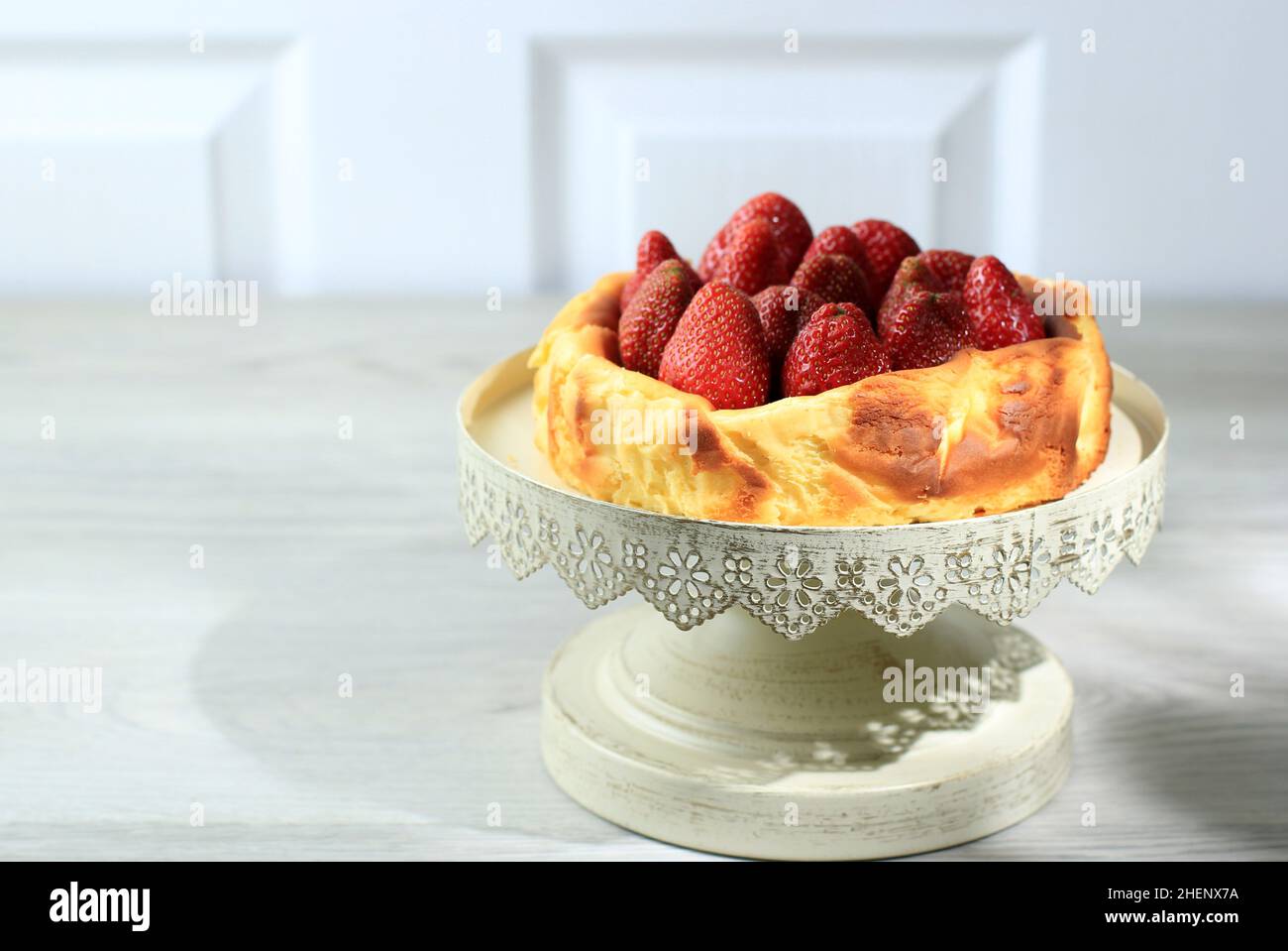 Torta di formaggio basco bruciata su sfondo nero, torta di formaggio virale con fragola sulla parte superiore. Spazio copia per testo Foto Stock