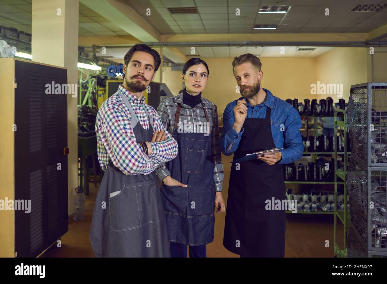 I giovani lavoratori che danno al loro capo o ispettore un giro intorno alla fabbrica di fabbricazione di scarpe Foto Stock