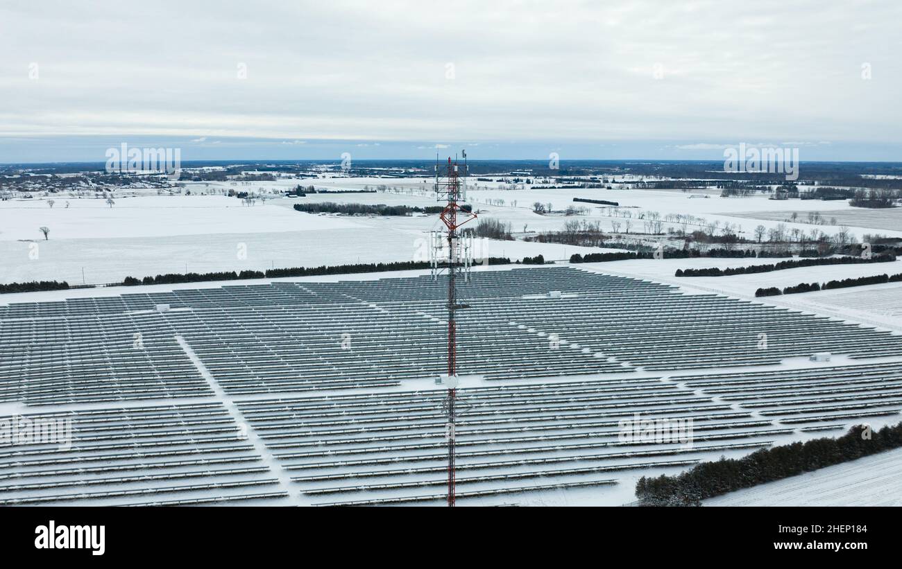 Una vista aerea, in piano, della parte superiore di una torre cellulare in una zona rurale, è vista in una giornata invernale coperta di neve. Foto Stock