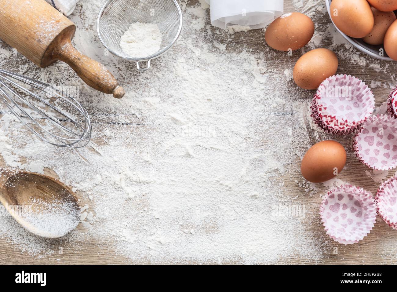 Utensili da cucina con uova, farina e cupcake sul tavolo da cucina - Vista dall'alto. Foto Stock