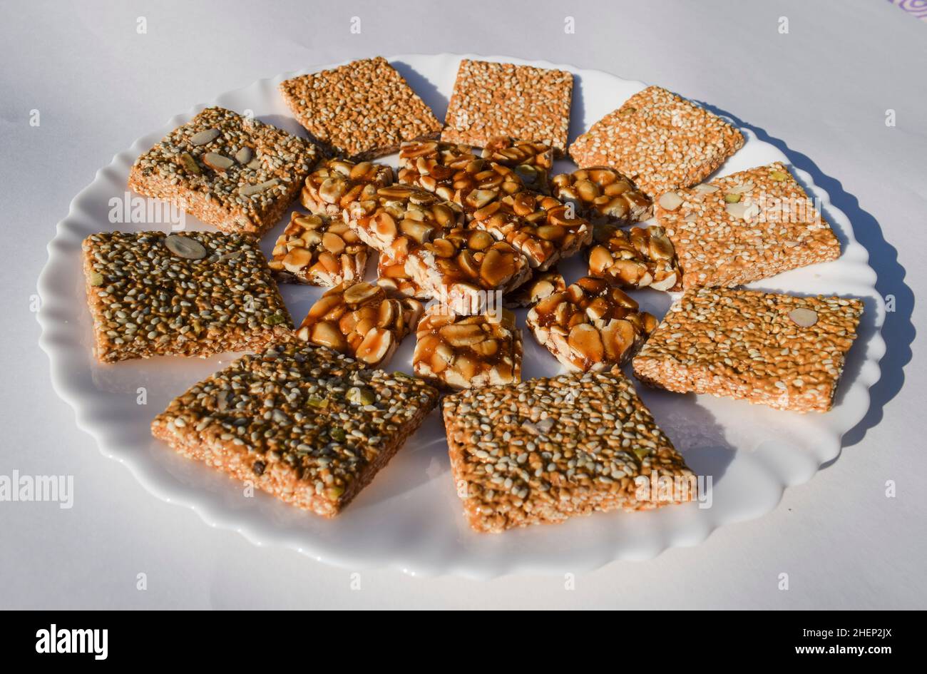 Gustose britles indiane di sesamo e barrette di caramelle di jaggery di Peanut conosciute come Til chikki e Peanut o shenga singhdana chikki decorati serviti durante Foto Stock