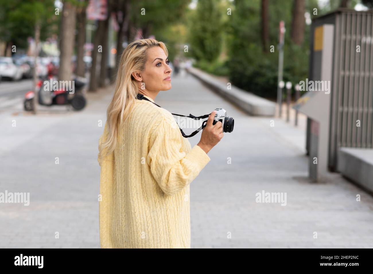 Donna con una macchina fotografica a piedi distratto sulla strada Foto Stock