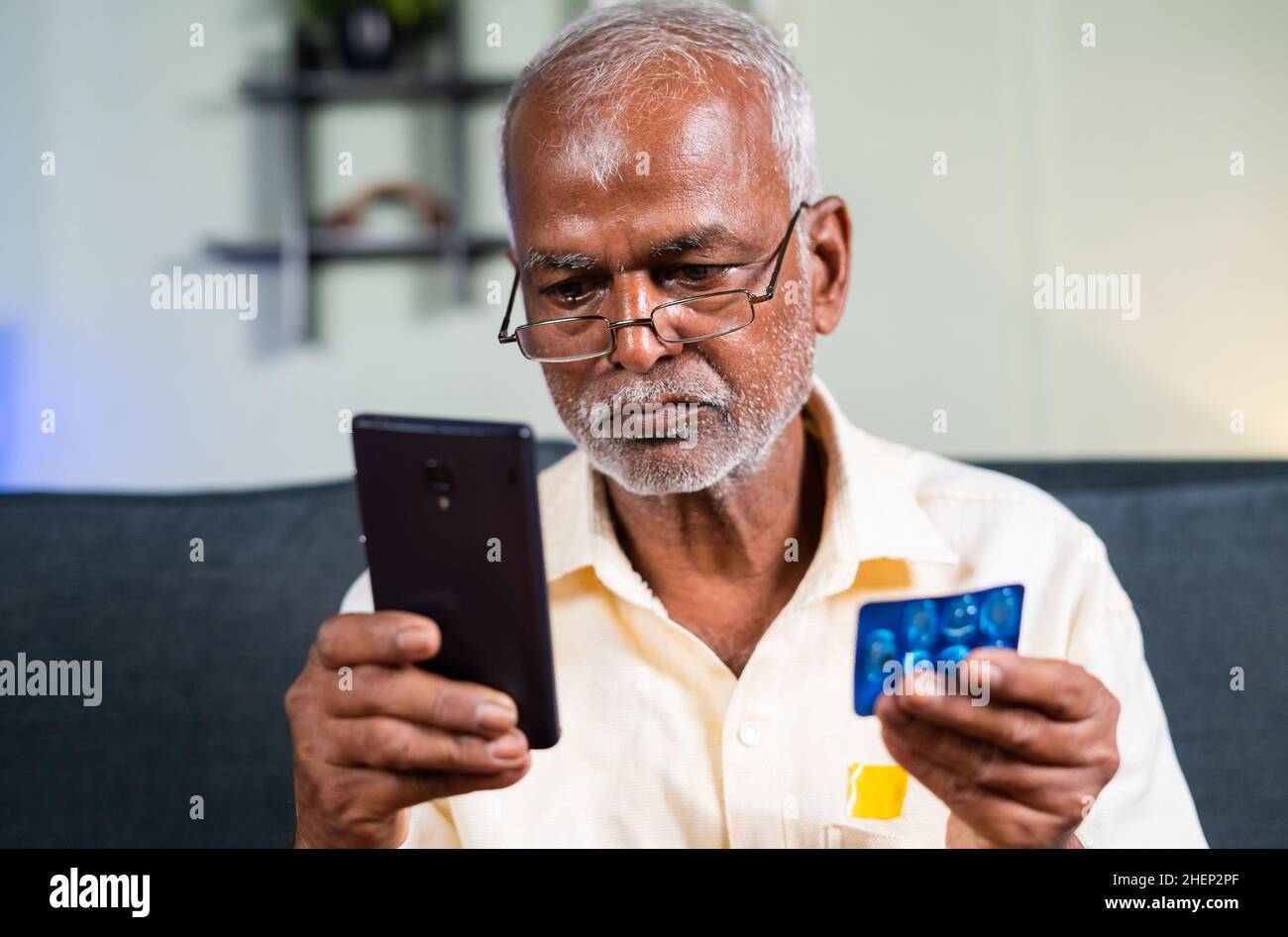 Primo piano di Senior man che controlla la disponibilità, l'acquisto o l'ordinazione di medicinali online sul cellulare da casa - concetto di e-Pharmacy Foto Stock