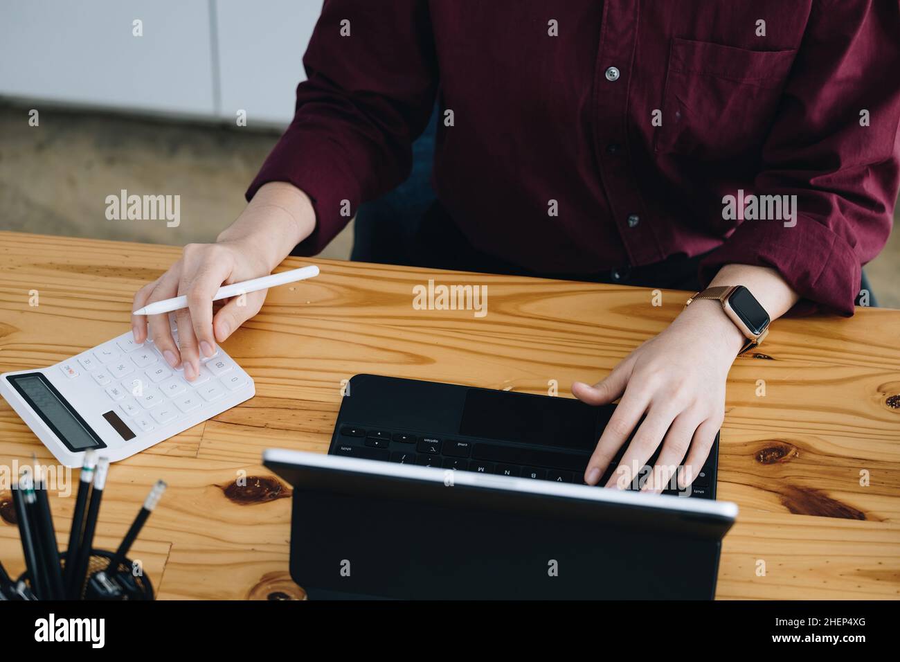Un dipendente di un'azienda femminile utilizza un calcolatore per calcolare il reddito di vendita su uno schermo di computer tablet via Internet. Foto Stock