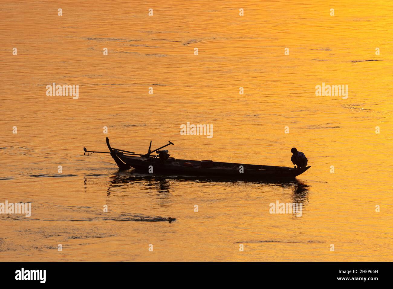 Pescatore sulla barca tradizionale sul fiume Mekong in Cambogia durante il tramonto Foto Stock