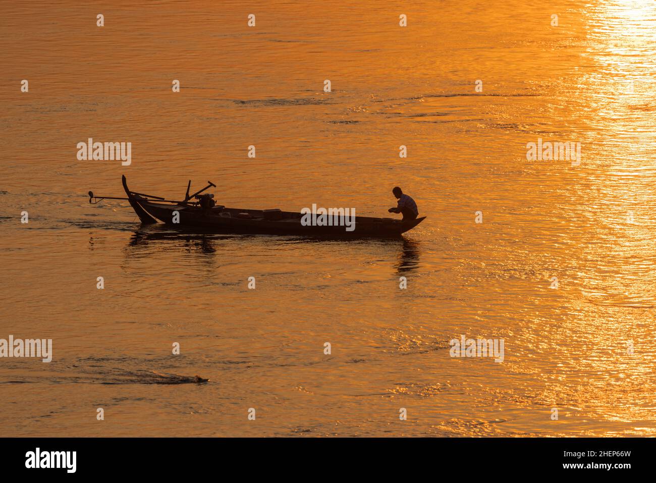 Pescatore sulla barca tradizionale sul fiume Mekong in Cambogia durante il tramonto Foto Stock