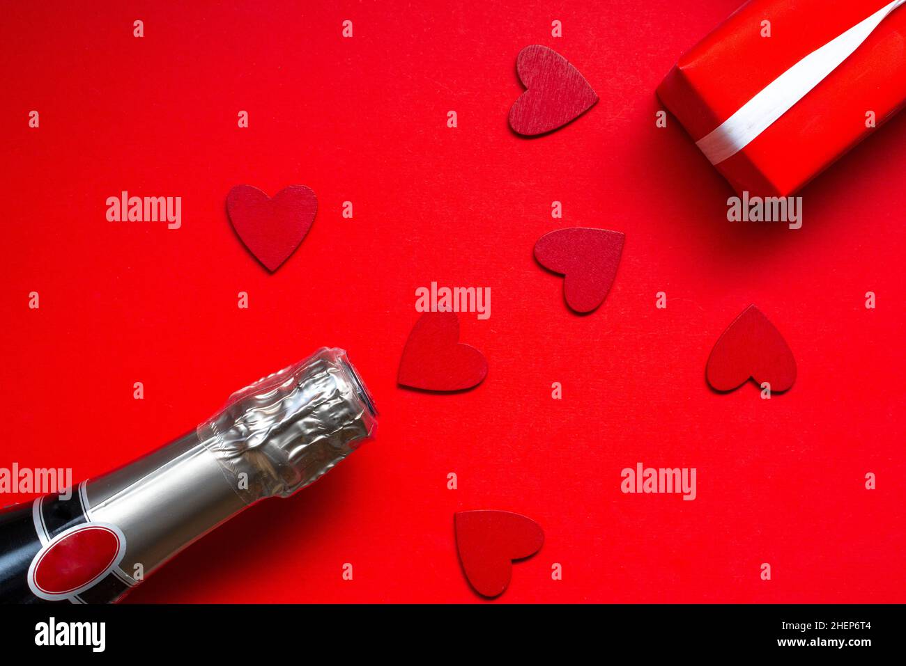 san valentino festa appartamento posato con una bottiglia di cappagne e regalo su sfondo rosso Foto Stock