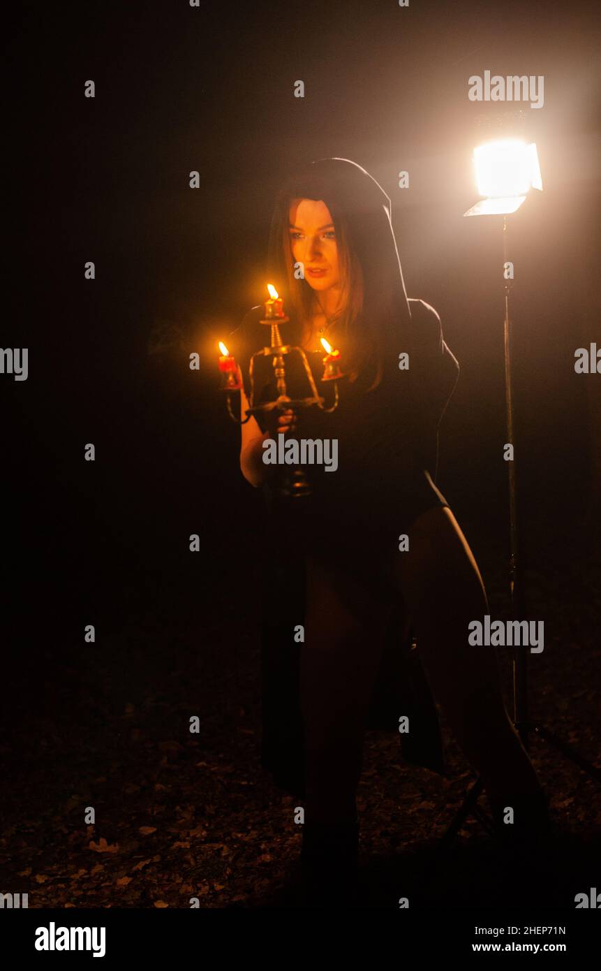 Giovane ragazza in una lunga notte di fuoco di cappotto nero Foto Stock