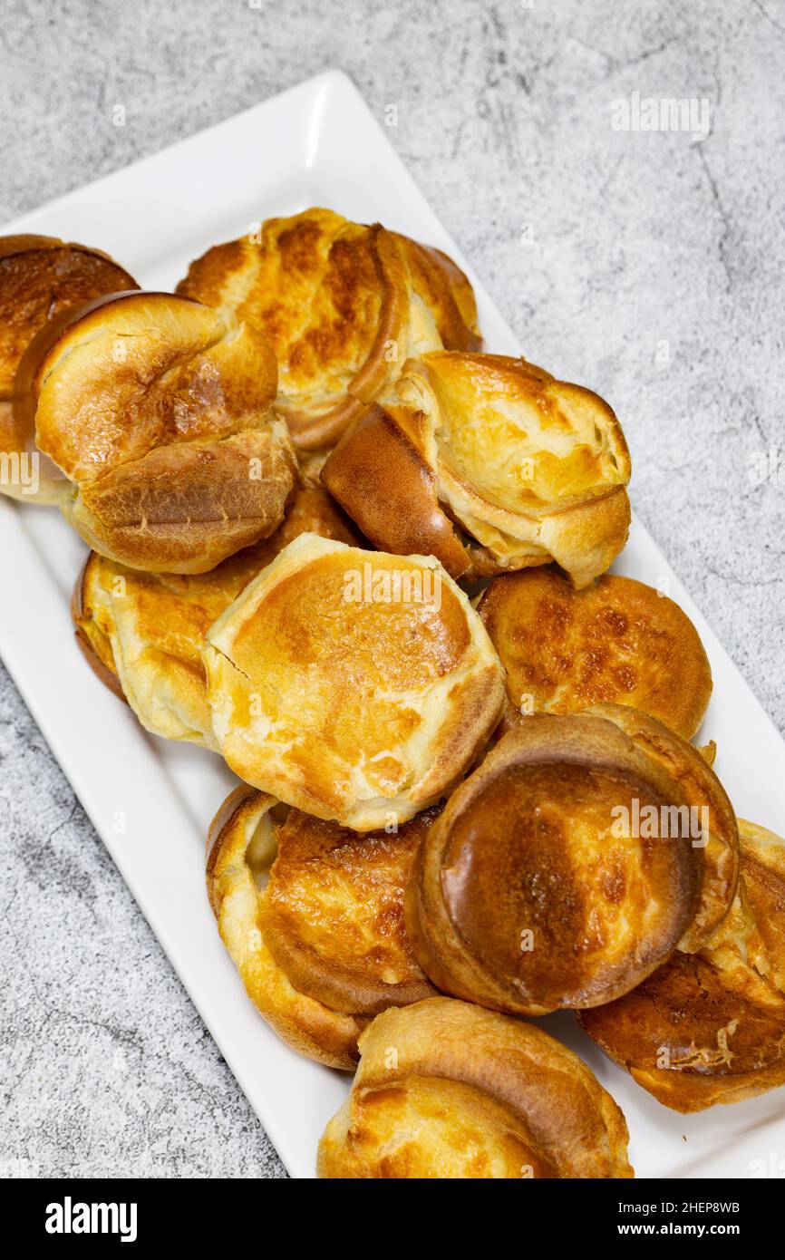 Budini individuali dello Yorkshire su una piastra rettangolare bianca. Cucina tradizionale britannica Foto Stock
