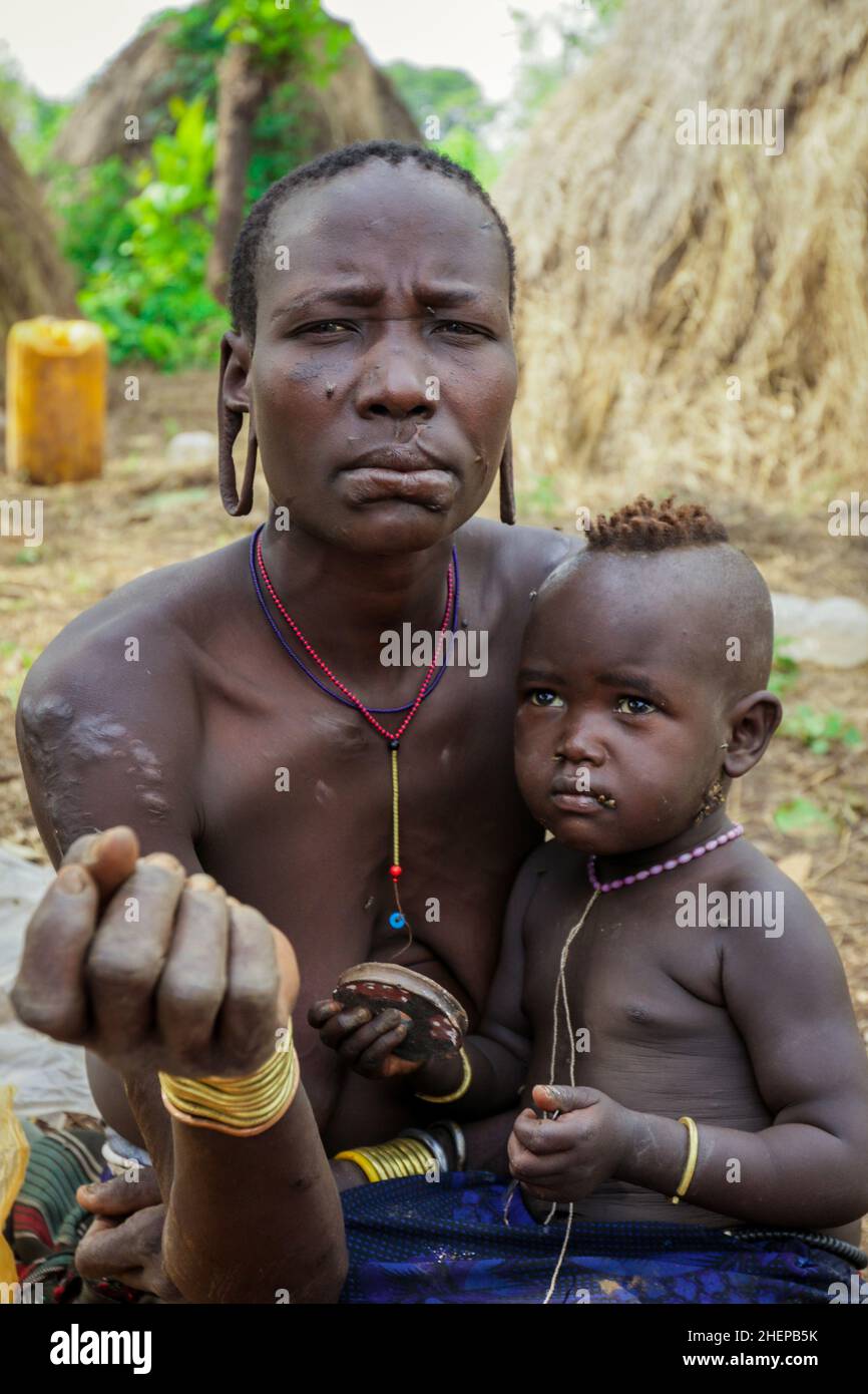 Mursi People Donne con bambino nel villaggio Tribe Foto Stock