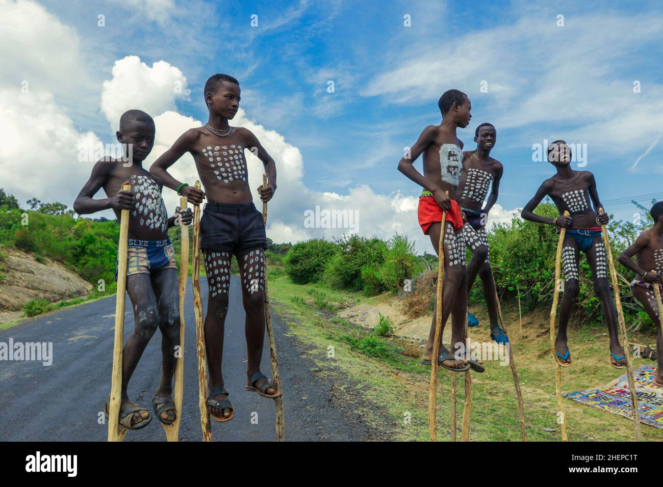 Ragazzi giovani di Benna Tribe con pittura tradizionale del corpo sui bastoncini lunghi di legno che posano per la foto Foto Stock