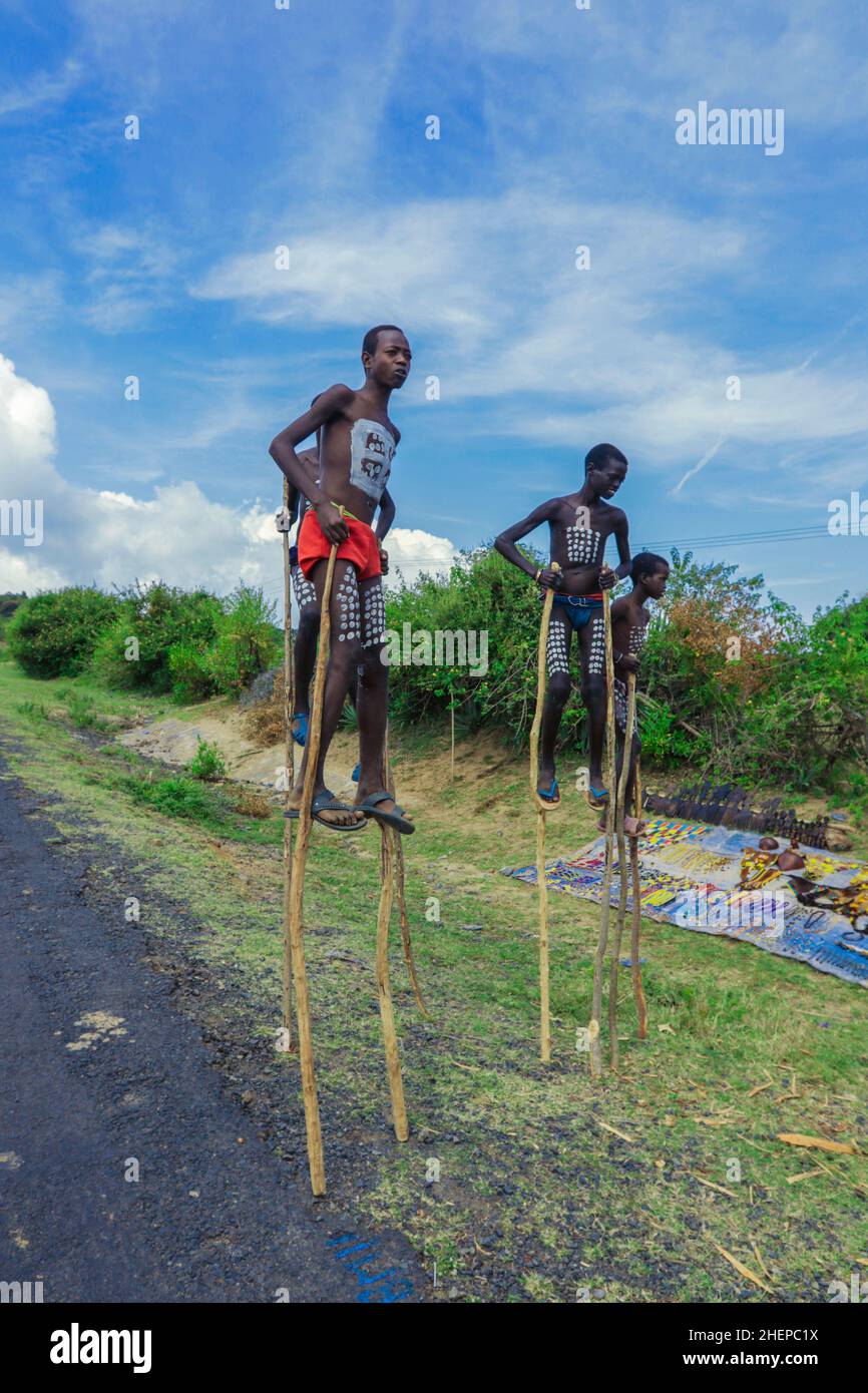 Ragazzi giovani di Benna Tribe con pittura tradizionale del corpo sui bastoncini lunghi di legno che posano per la foto Foto Stock