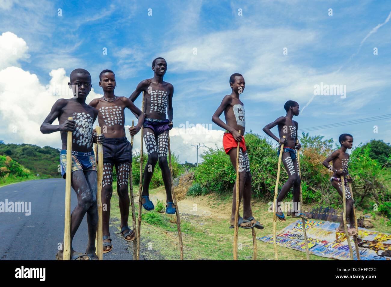 Ragazzi giovani di Benna Tribe con pittura tradizionale del corpo sui bastoncini lunghi di legno che posano per la foto Foto Stock