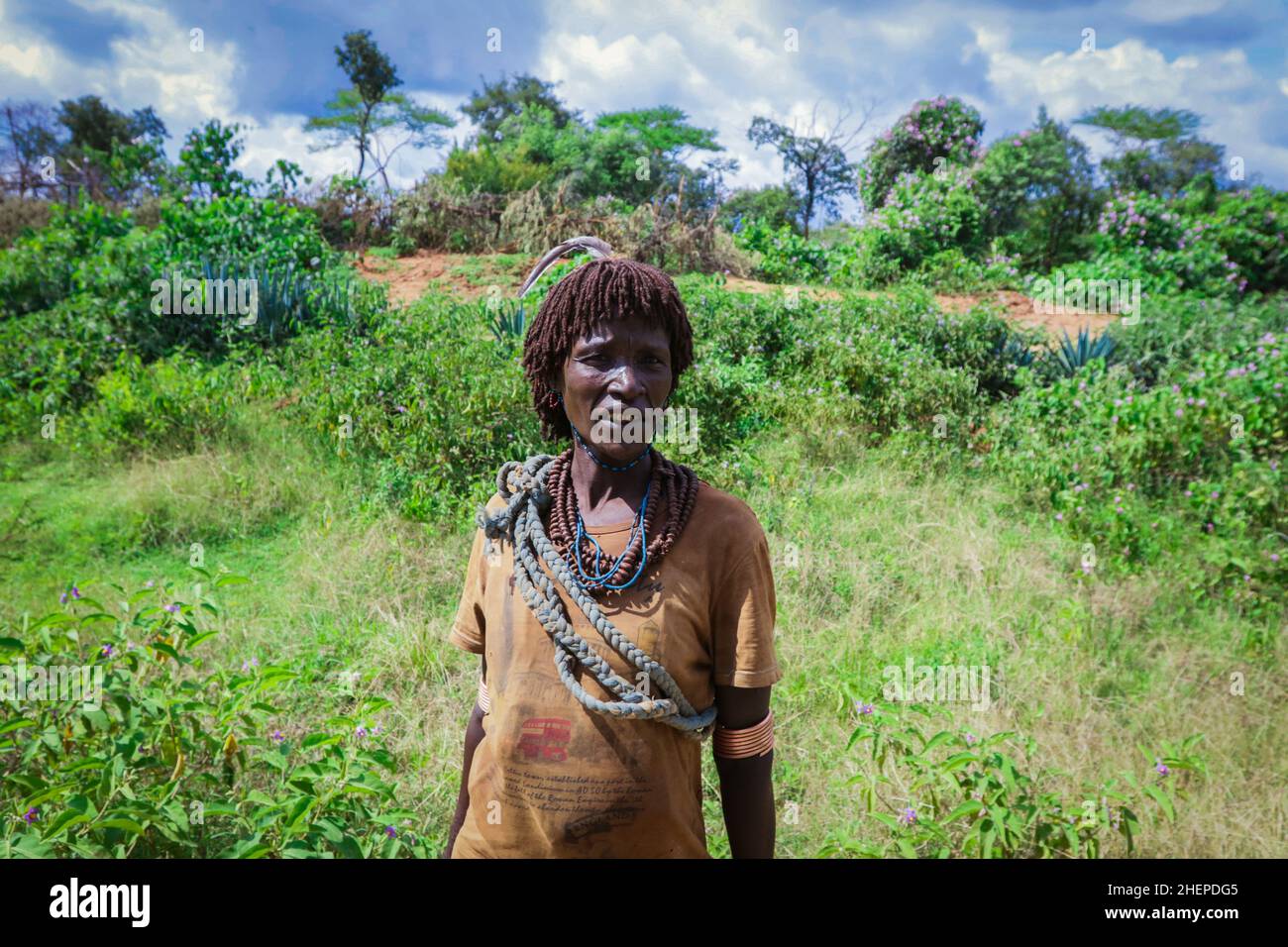 Le donne stanche di Hamer Tribe ritornano dal lavoro agricolo dalla strada rurale verde Foto Stock