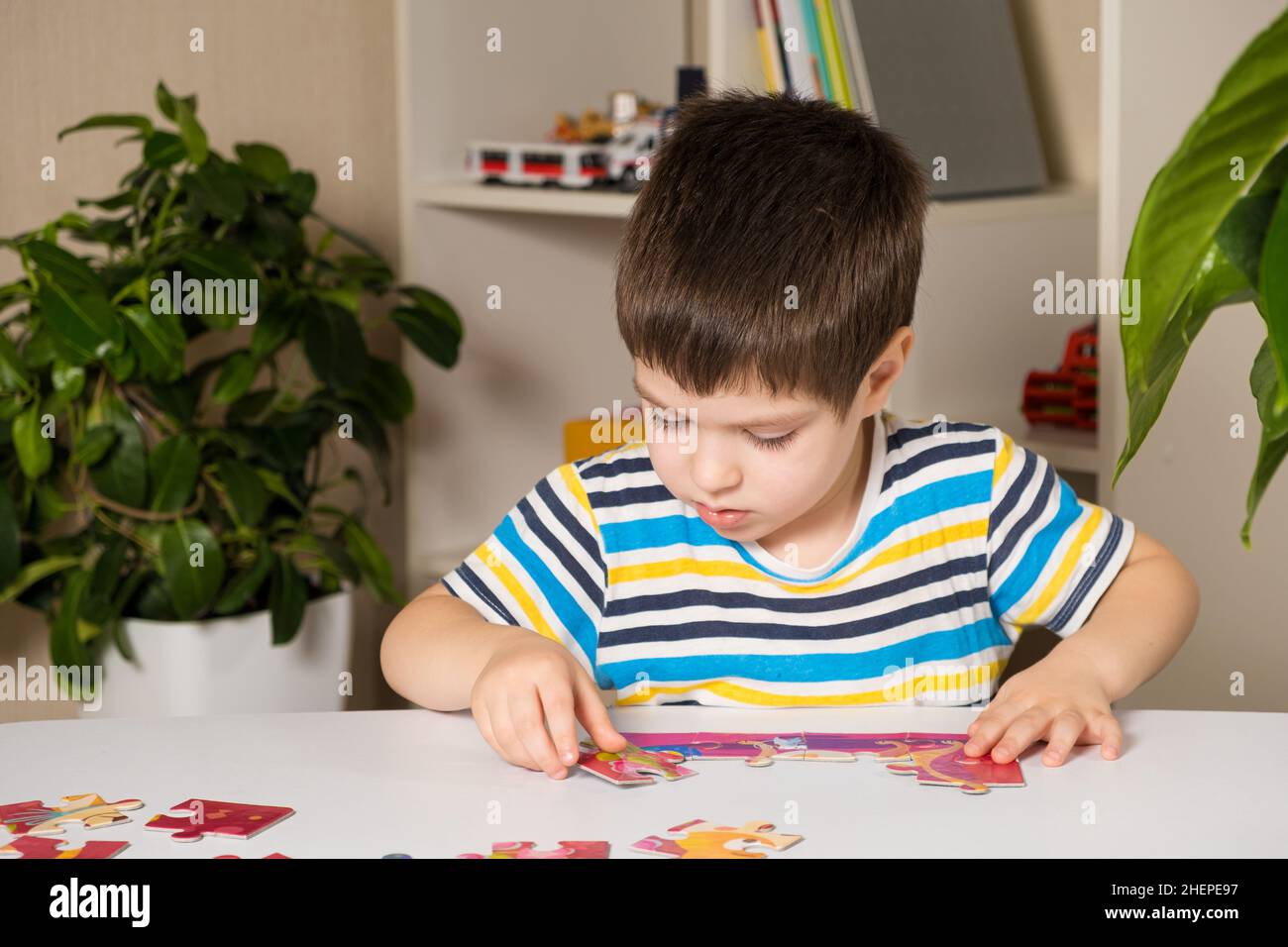 Un preschooler suona puzzle, mette insieme un'immagine Foto Stock
