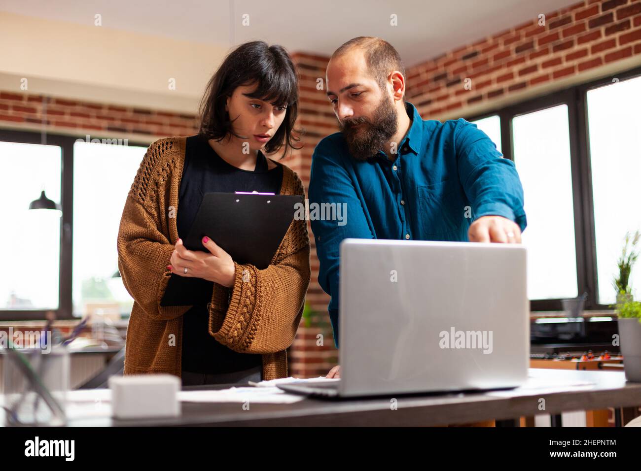 Uomo d'affari che spiega le idee di vendita alla donna del direttore che mostra il tasso di dati sul computer portatile che discute la strategia dell'azienda. Colleghi che lavorano alla presentazione di affari nell'ufficio di startup Foto Stock