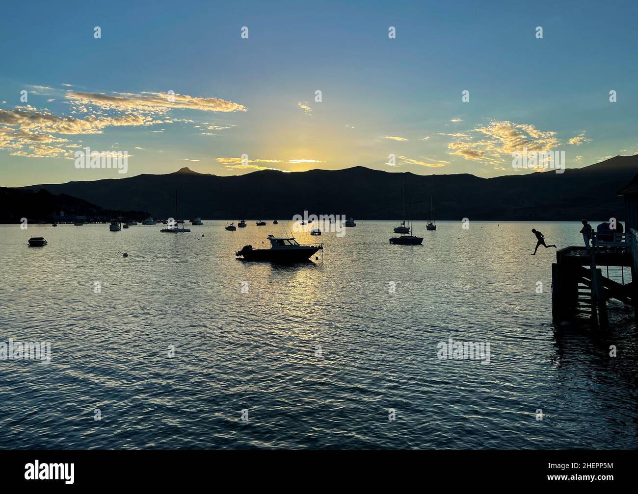 Akaroa, Nuova Zelanda. 11th Jan 2022. Un ragazzo salta in acqua al porto di Akaroa, Nuova Zelanda, 11 gennaio 2022. L'estate è di solito la stagione più alta per il turismo in questa città, ma quest'anno, Akaroa non è così occupato come prima a causa dell'impatto di COVID-19. Credit: Guo Lei/Xinhua/Alamy Live News Foto Stock