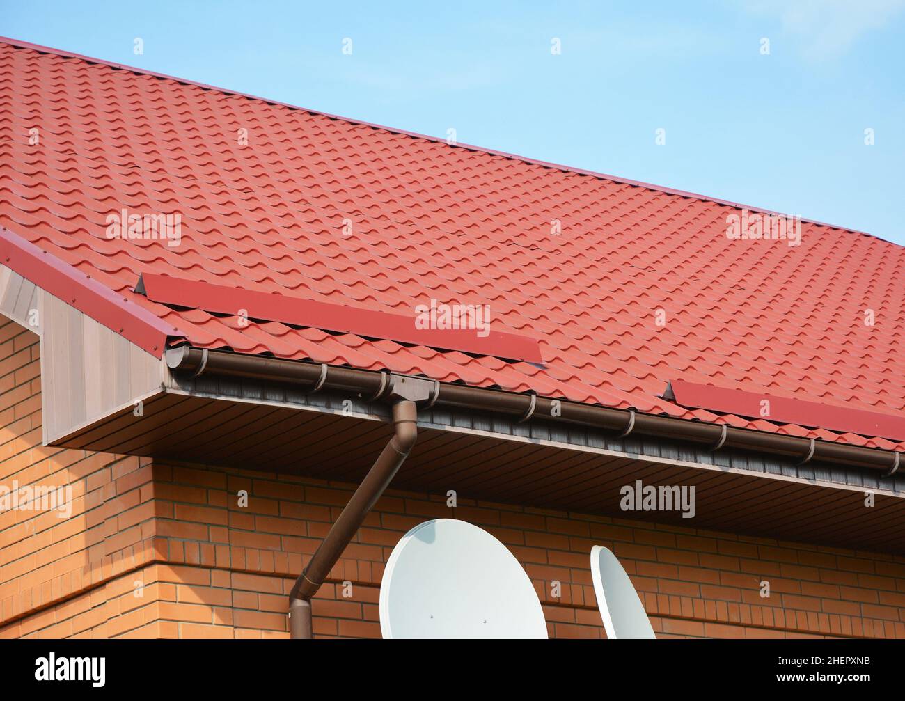 Primo piano sul nuovo sistema gocciolatoio e protezione del tetto dalla tavola da neve. Red Roofing Construction. Foto Stock