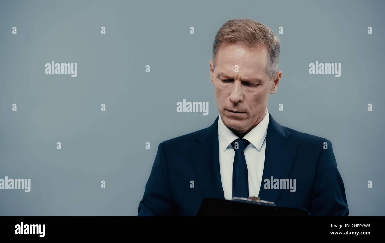 Uomo d'affari in abbigliamento formale che tiene appunti isolato sul grigio Foto Stock