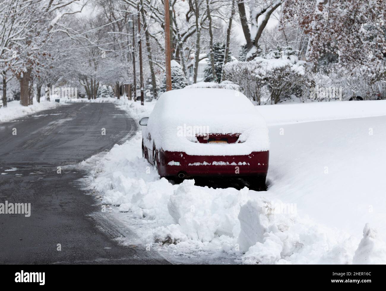 Un'auto parcheggiata in strada che impedisce alle città spazzaneve di sgombrare la strada in un quartiere residenziale. Foto Stock