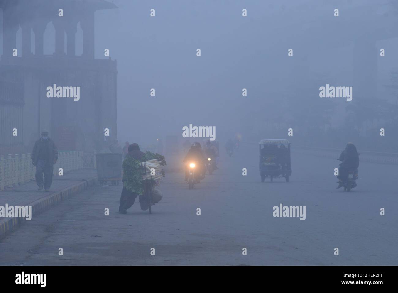 Cittadini pakistani, studenti in viaggio durante una fredda e densa mattinata di smog a Lahore, Pakistan, il 11 gennaio 2022. I residenti e i pendolari pakistani sono più preoccupati che sorpresi a causa dello strato improvviso di smog denso che sta causando problemi di respirazione, visibilità e ha anche ostacolato il flusso regolare del traffico che ha ridotto la visibilità per i pendolari e ha provocato diverse lamentele di problemi respiratori e angoscia mentale. (Foto di Rana Sajid Hussain / Pacific Press/Sipa USA) Foto Stock