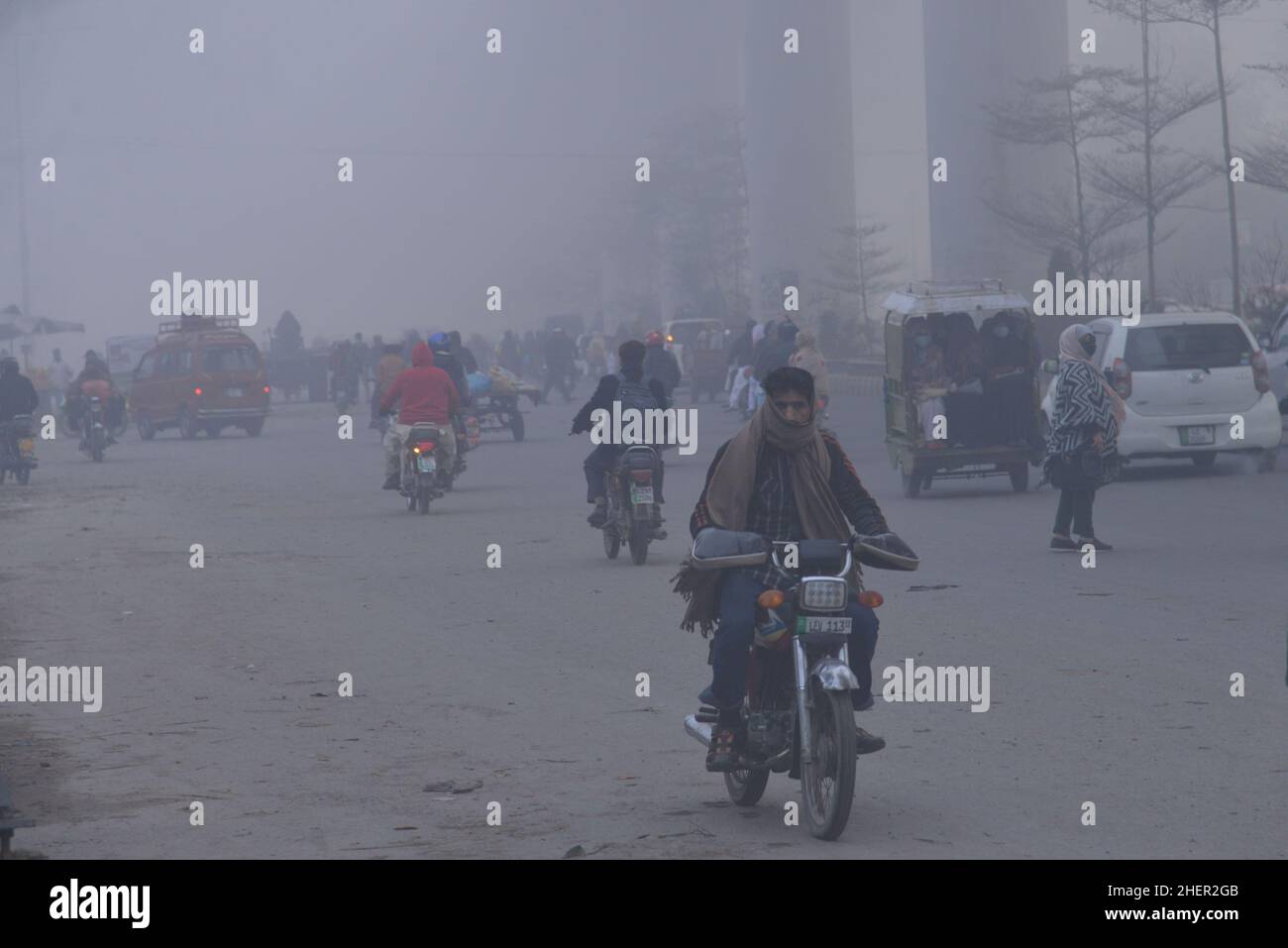 Cittadini pakistani, studenti in viaggio durante una fredda e densa mattinata di smog a Lahore, Pakistan, il 11 gennaio 2022. I residenti e i pendolari pakistani sono più preoccupati che sorpresi a causa dello strato improvviso di smog denso che sta causando problemi di respirazione, visibilità e ha anche ostacolato il flusso regolare del traffico che ha ridotto la visibilità per i pendolari e ha provocato diverse lamentele di problemi respiratori e angoscia mentale. (Foto di Rana Sajid Hussain / Pacific Press/Sipa USA) Foto Stock