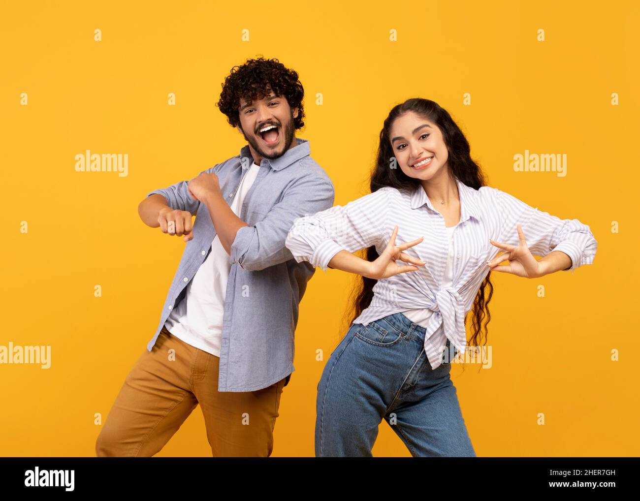 Divertirsi. Gioiosa giovane coppia indiana che balla e che si gira intorno, godendo insieme la musica nazionale preferita Foto Stock