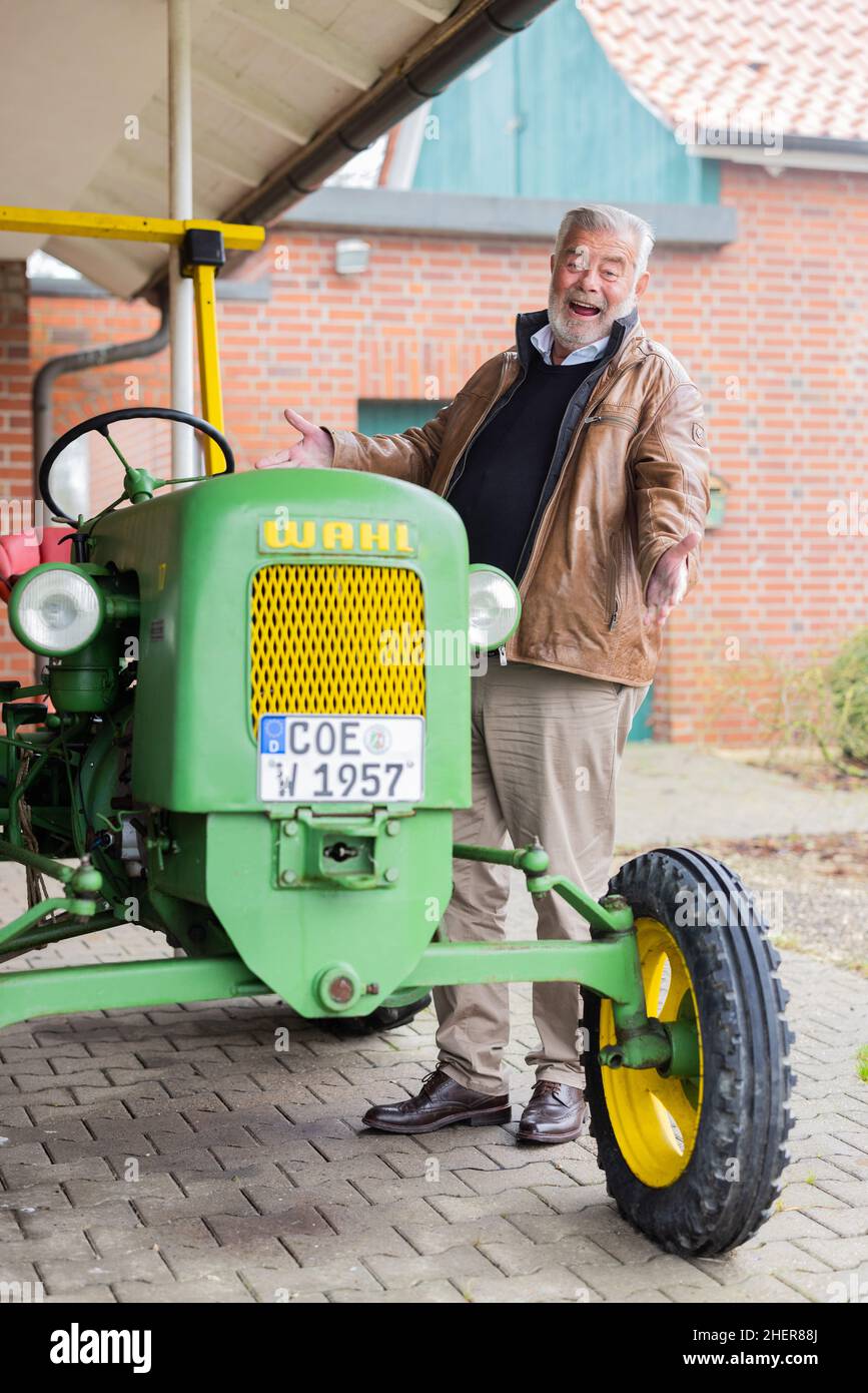 Senden, Germania. 12th Jan 2022. Harry Wijnvoord, presentatore olandese ('il prezzo è caldo'), si trova di fronte alla sua casa accanto al suo trattore storico (1957) del marchio Maschinenfabrik Carl Fr. Wahl. Credit: Rolf Vennenbernd/dpa/Alamy Live News Foto Stock