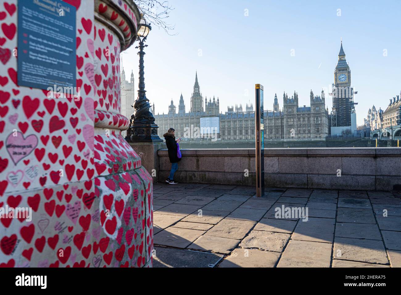 WESTMINSTER, LONDRA, REGNO UNITO. 12 gennaio 2022. La gente cammina al sole del pomeriggio lungo il National Covid Memorial Wall dipinto con cuori rossi sull'argine del Tamigi per commemorare le vittime della pandemia del COVID-19 il giorno in cui il primo ministro Boris Johnson ha affrontato l'esame in Parlamento dopo aver ammesso di aver partecipato a una festa in giardino a Downing Street il 20 Maggio 2020, in un momento in cui il Regno Unito era soggetto a restrizioni per il coronavirus. Credit: amer Ghazzal/Alamy Live News Foto Stock