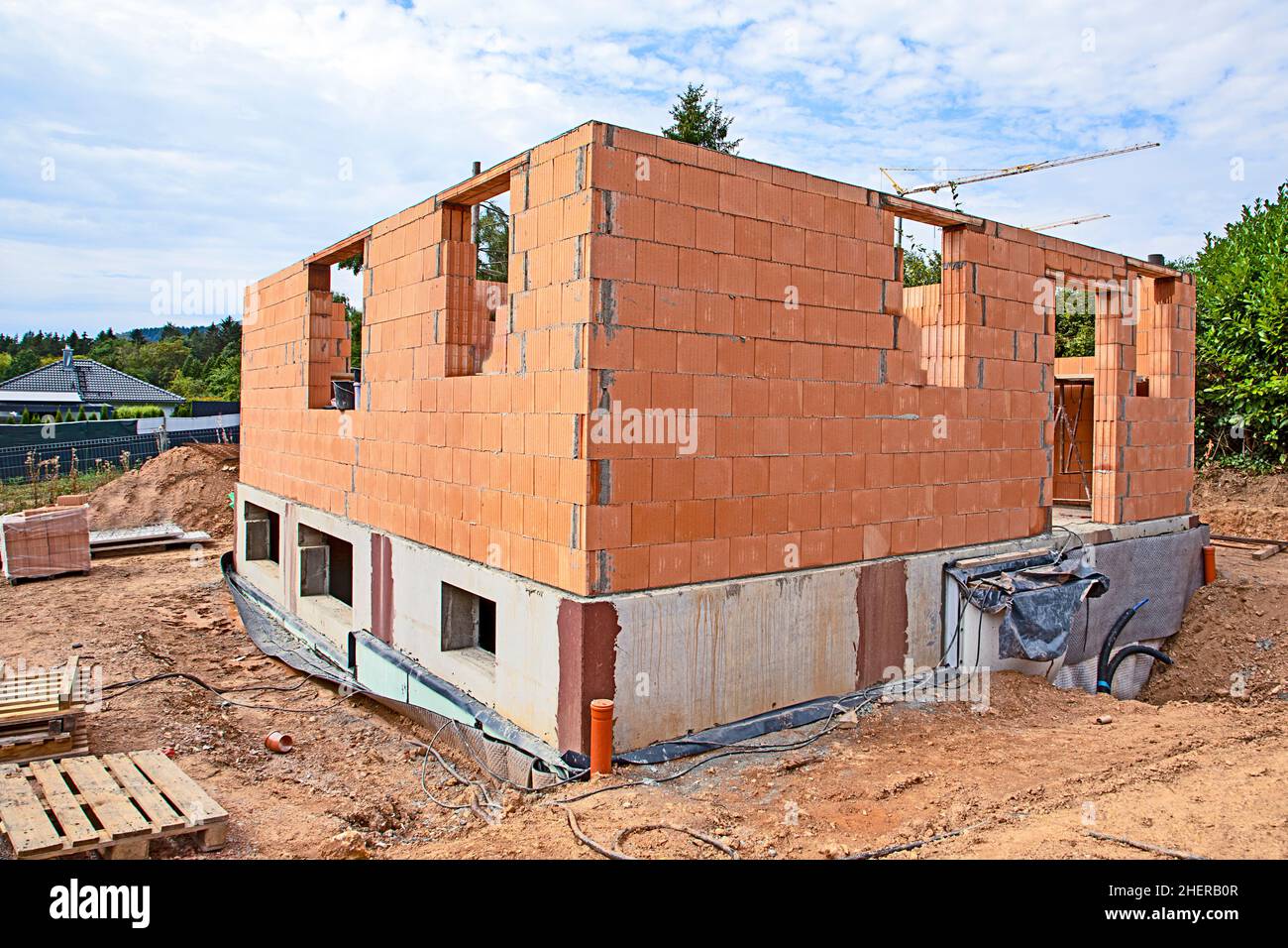 piccola casa in costruzione con cantina e pietre rosse muro per costruire il piano terra Foto Stock