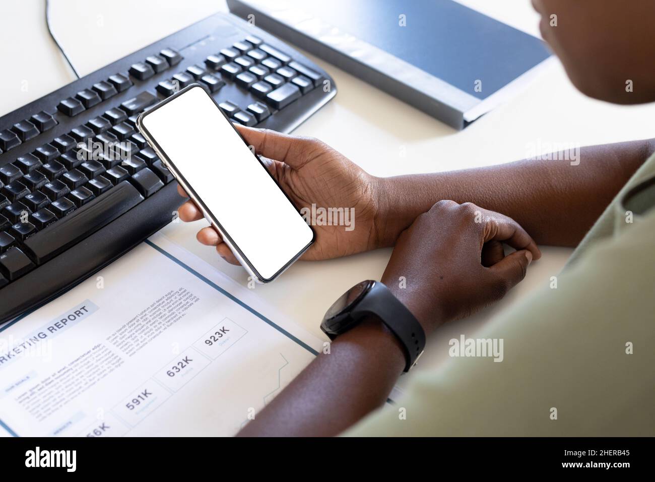 Immagine ritagliata di un professionista femminile utilizzando uno smartphone con spazio per la copia presso la scrivania del computer in ufficio Foto Stock