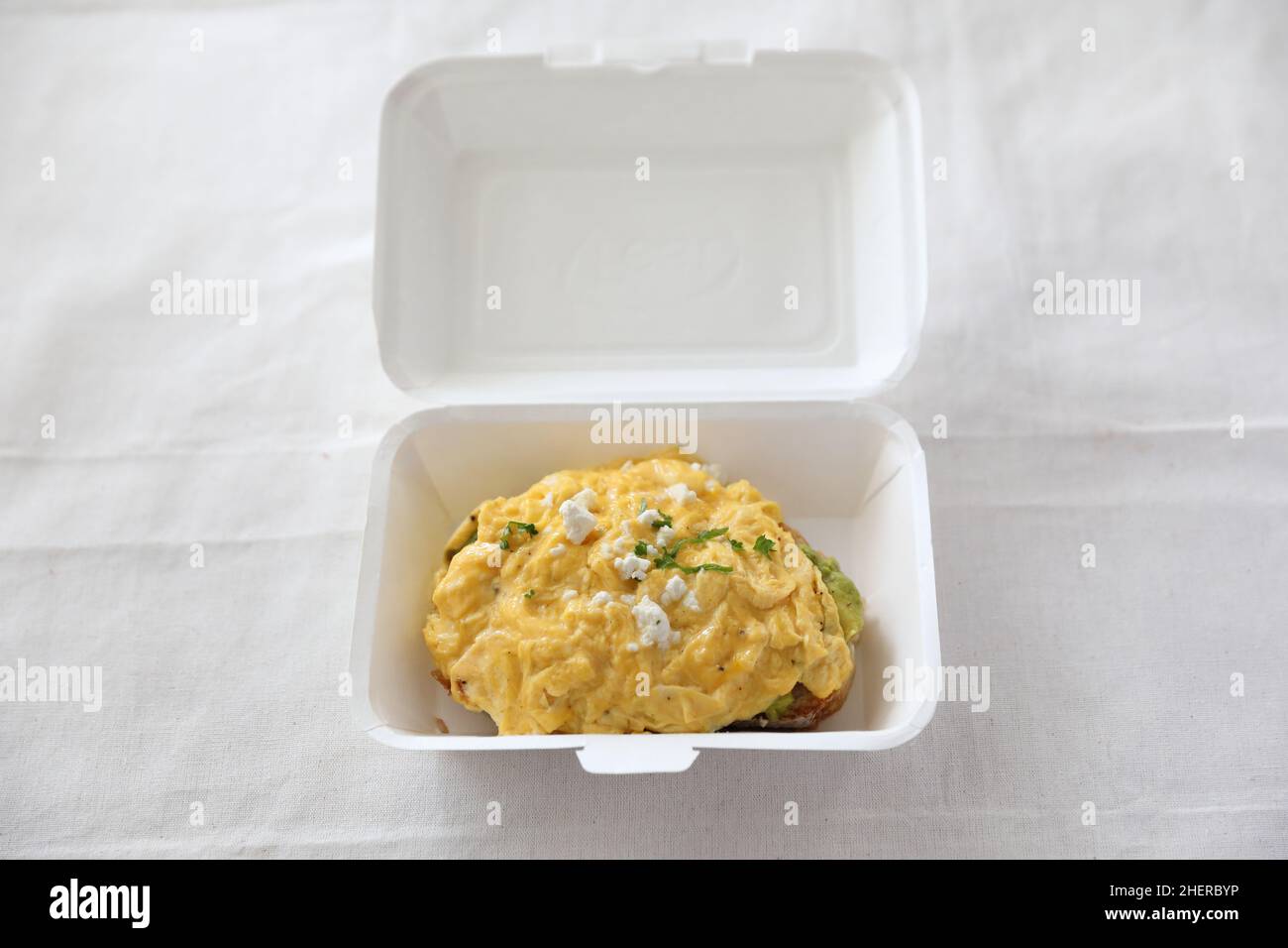 Avocado e toast con uova strapazzate con consegna a domicilio su sfondo bianco Foto Stock