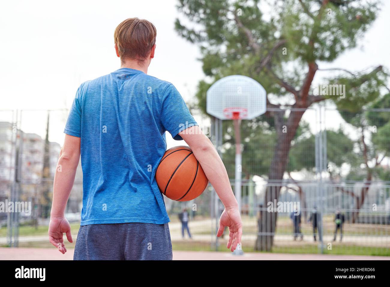 giocatore di basket che guarda il cestino prima di lanciare. giovane uomo con la palla e abbigliamento sportivo. Foto Stock