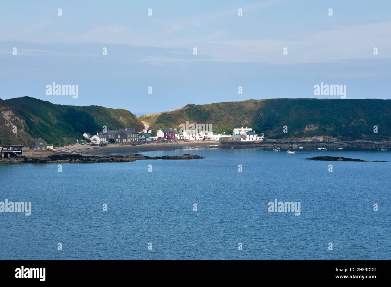 La luce del sole sceglie il villaggio sulla spiaggia a Porth Dullaen, Galles del Nord sulla sua penisola rocciosa Foto Stock