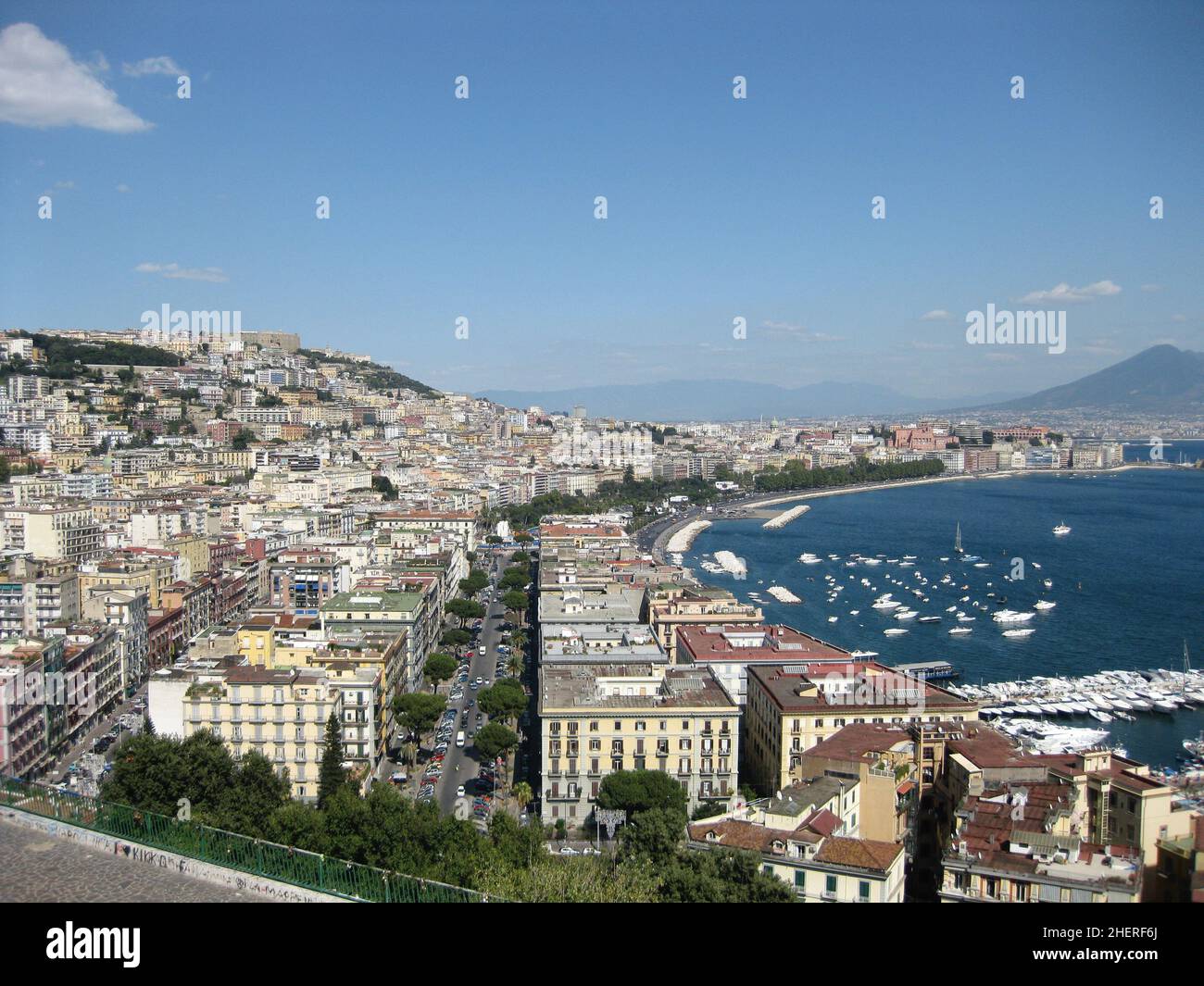 Vista dall'alto di Napoli con case colorate lungo il porto di Napoli con il Vesuvio sullo sfondo e barca sul mare. Foto Stock