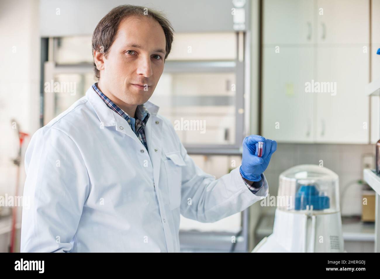 Tecnico di laboratorio di sesso maschile che tiene una provetta con campione in laboratorio medico o scientifico Foto Stock