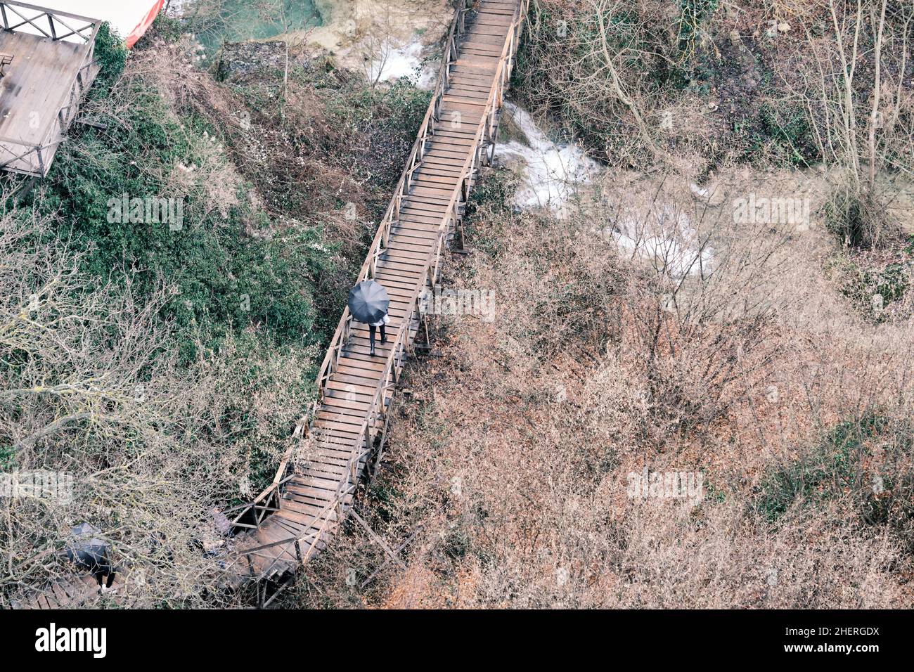Vista aerea, durante le giornate piovose, le persone trasportano l'ombrello, le persone camminano sul ponte di legno e camminano sul ponte. Foto Stock