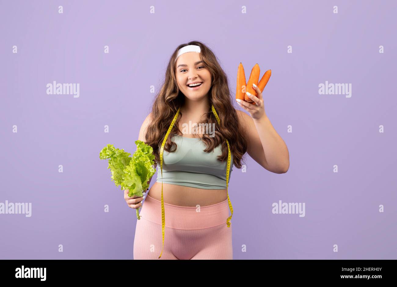 Allegro millenario europeo Plus size fit donna in uniforme sportiva con nastro di misurazione e verdure Foto Stock