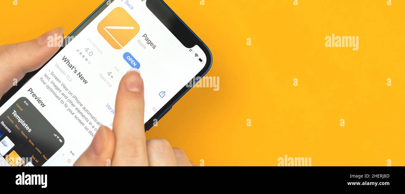 Kharkov, Ucraina - 10 gennaio 2022: Primo piano dell'icona dell'app Apple Pages, disegno di striscioni. La donna utilizza l'applicazione su Apple iPhone 12 Foto Stock