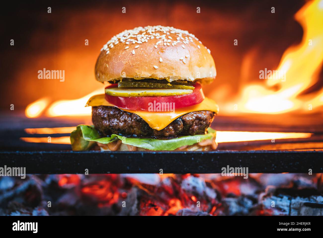 Burger, cheeseburger su carbone barbecue con fuoco in sfondo sfocato. Immagine reale. Hamburger classico Foto Stock