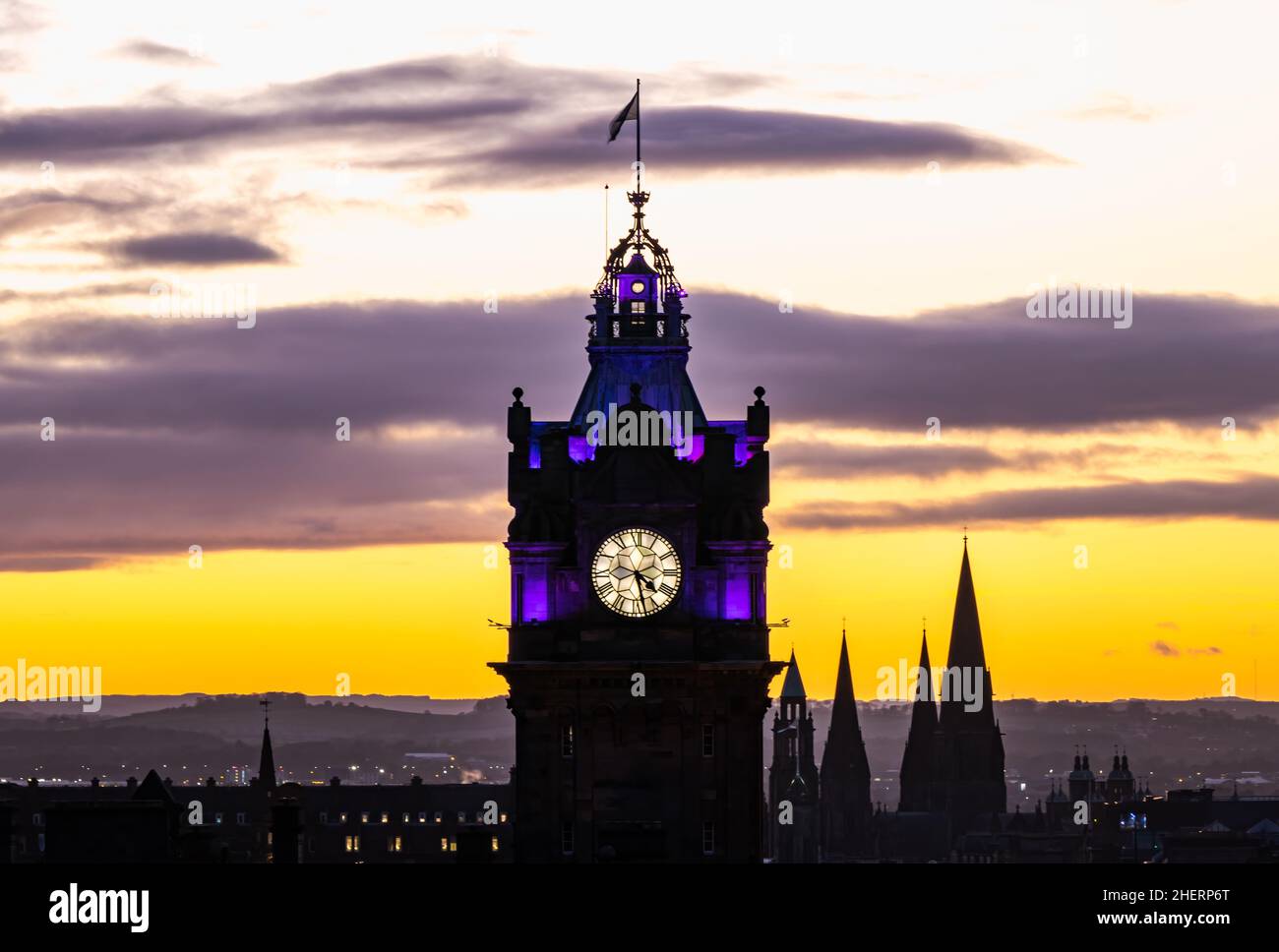 Torre dell'orologio Balmoral illuminata di notte con un tramonto colorato, Edimburgo, Scozia, Regno Unito Foto Stock