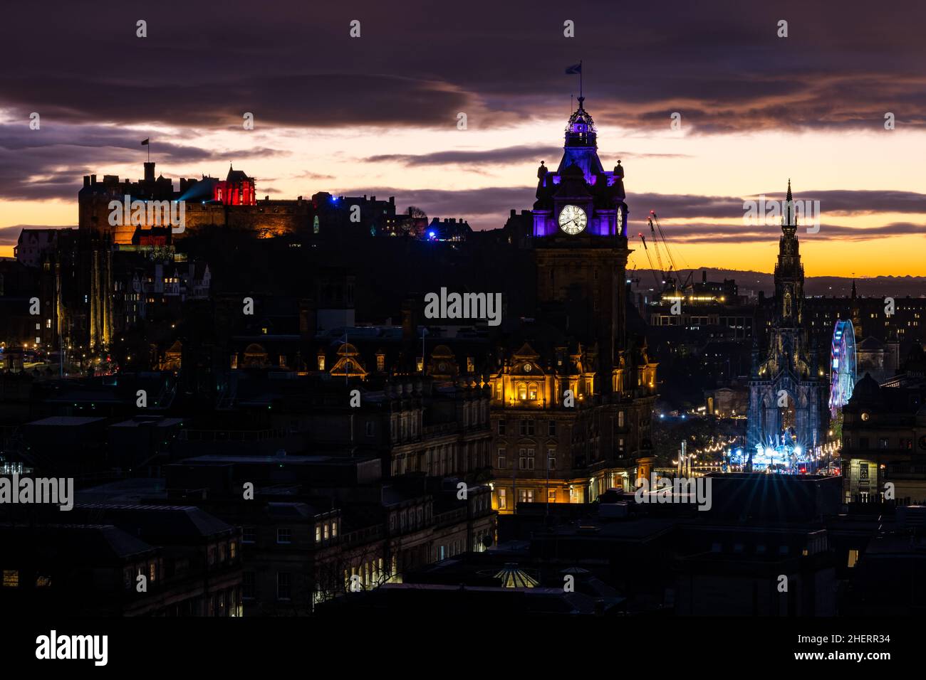 Castello di Edimburgo e Torre dell'orologio Balmoral illuminata di notte con tramonto colorato, Edimburgo, Scozia, Regno Unito Foto Stock