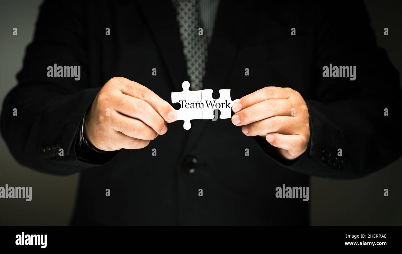 uomo d'affari che tiene un seghetto alternativo in mano. La parola lettera lavoro di squadra. Lavorare come un concetto di squadra e la teoria del lavoro di coordinamento di gruppo nell'organizzazione Foto Stock