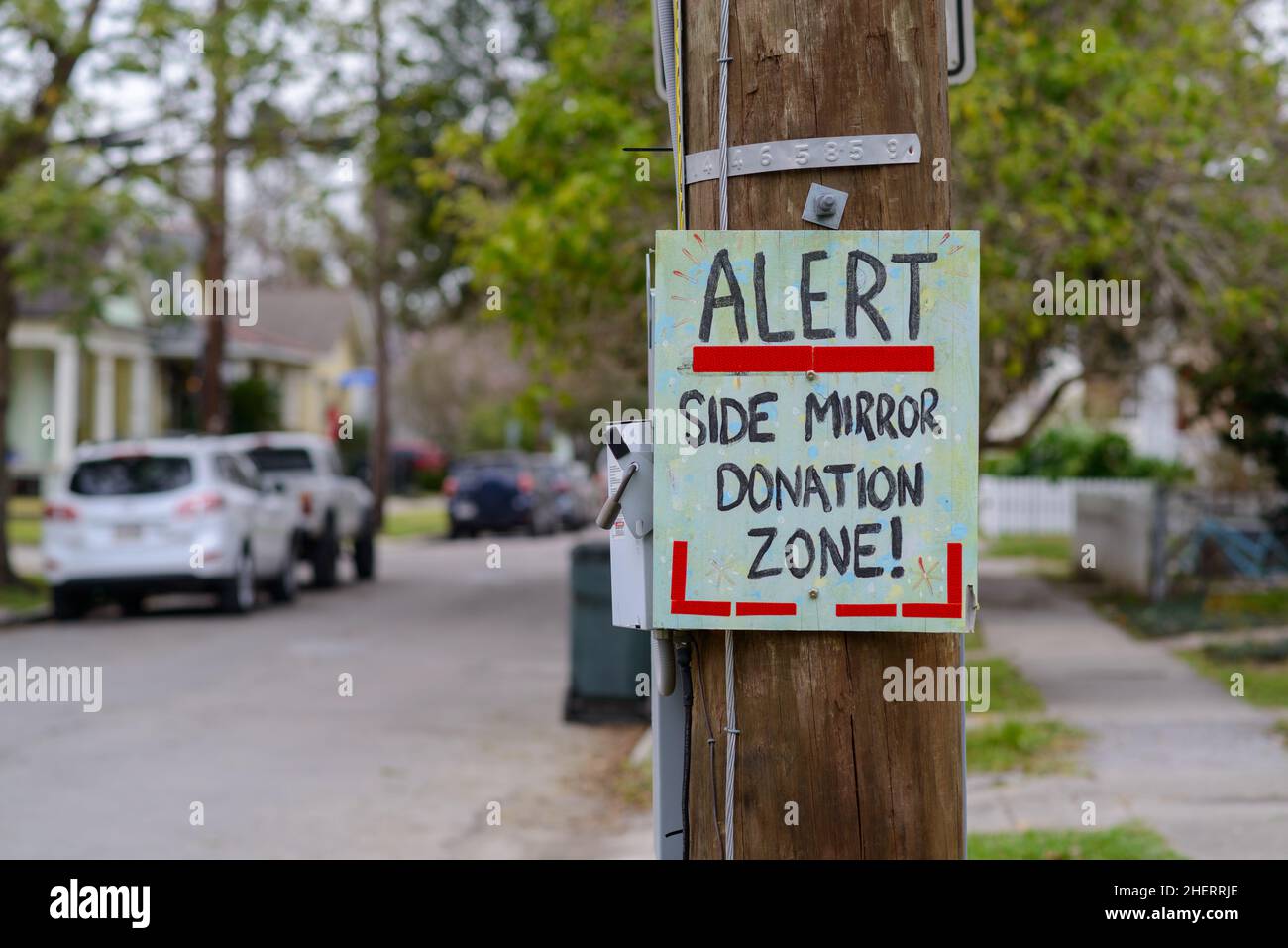 Cartello "ALERT Side Mirror Donation zone" attaccato al polo di servizio sulla stretta Uptown Street a New Orleans, LA, USA Foto Stock