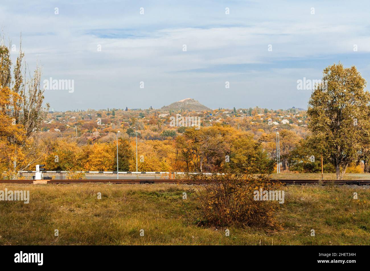 Autunno paesaggio soleggiato. Vista di una città mineraria autunnale con alberi e foglie gialle cadute a terra in un giorno di sole ottobre. Modello per la progettazione. Foto Stock