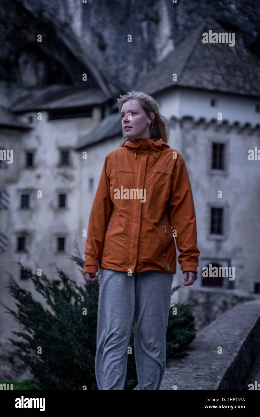 Giovane ragazza femminile, donne di fronte al castello Predjama - Predjamski grad in primavera, Slovenia Foto Stock