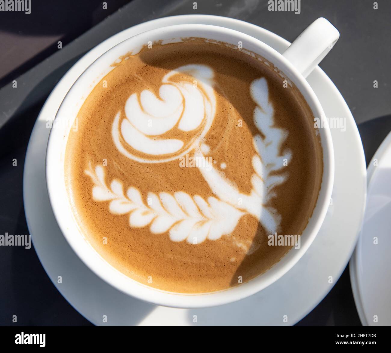 caffè con un fiore formato con schiuma di latte in una tazza bianca Foto Stock