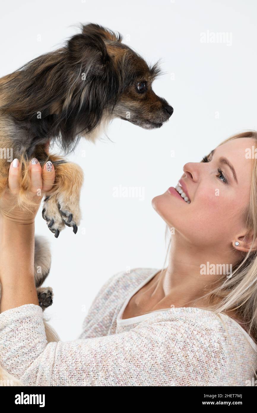 Ragazza ha sollevato il suo cane e stanno guardando gli occhi l'uno dell'altro. Ritratto di una donna con un cane. Cane di razza multipla. Foto Stock